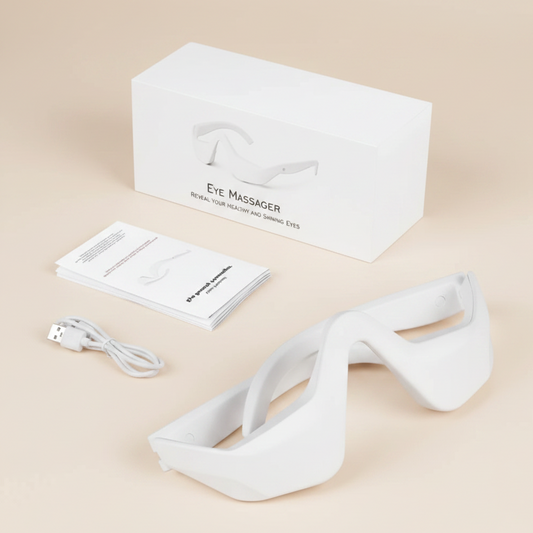 White eye massager with packaging, user manual, and USB cable on a beige background